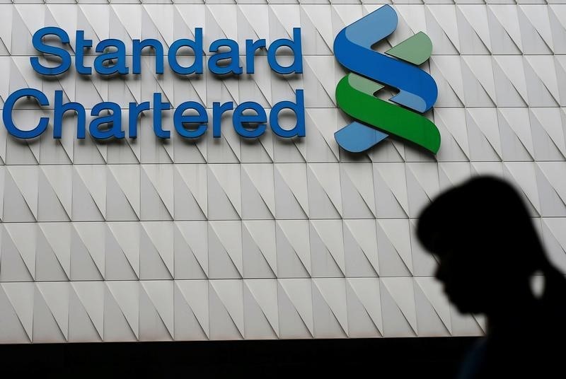 © Reuters. A woman walks past Standard Chartered logo at its headquarters in Hong Kong