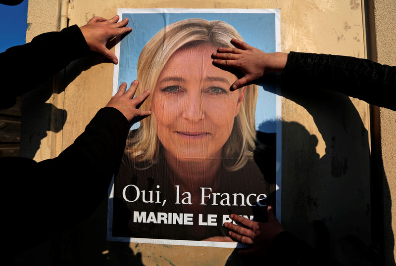 © Reuters. Supporters paste a poster of Marine Le Pen, France's National Front leader, on a wall before a political rally for local elections in Frejus