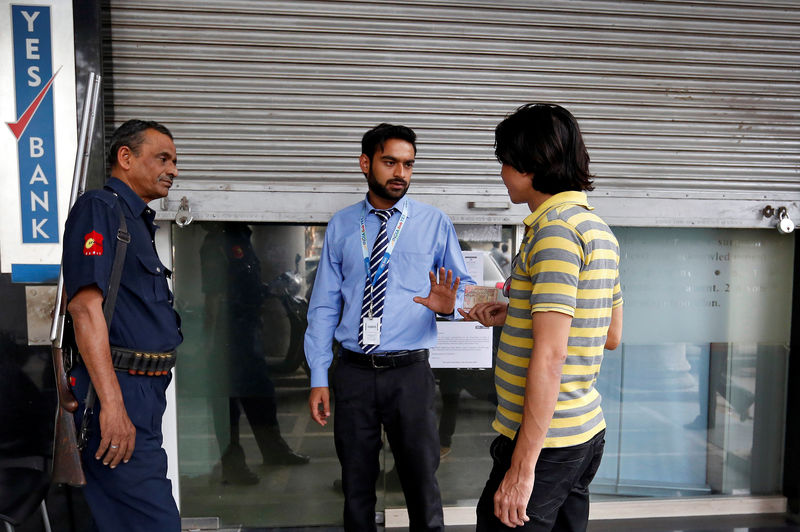 © Reuters. An employee speaks with a man holding 1000 rupee notes outside a Yes Bank branch in New Delhi