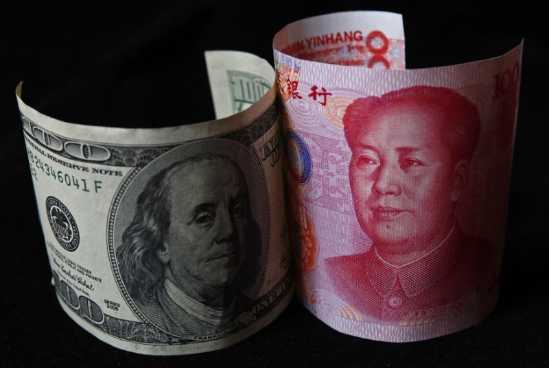 © Reuters. A 100 yuan banknote is placed next to a $100 banknote in this picture illustration taken in Beijing