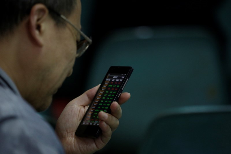 © Reuters. An investor checks stock information on a mobile phone at a brokerage house in Shanghai