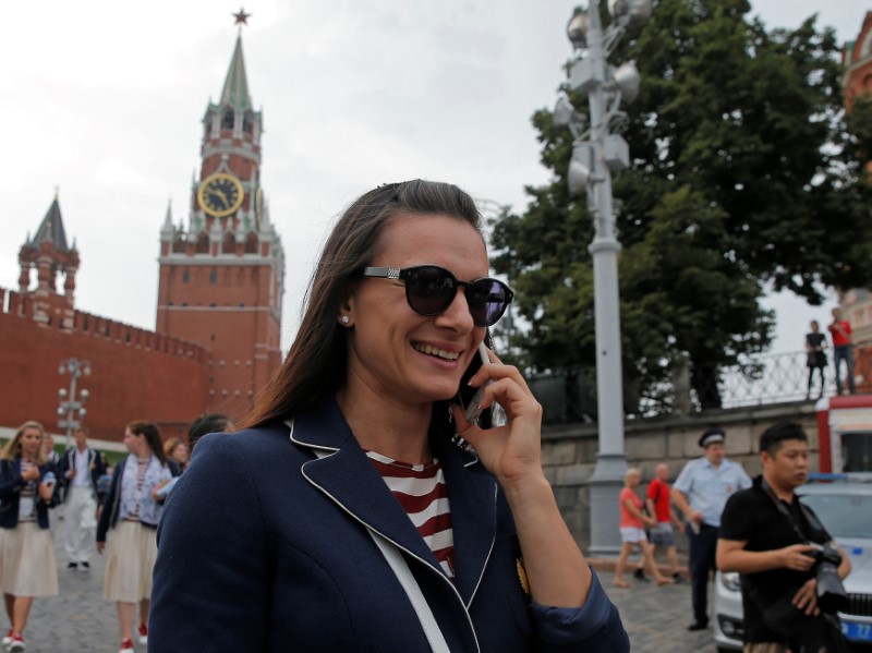 © Reuters. Russian track-and-field athlete Isinbayeva talks on her mobile phone as she walks at Red Square in Moscow