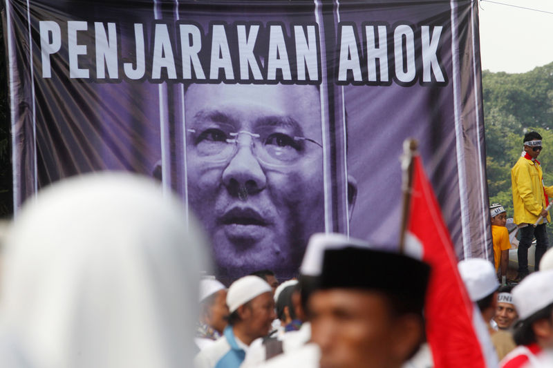 © Reuters. Members of hardline Muslim groups stand around a poster during protest against Jakarta's incumbent governor Basuki Tjahaja Purnama, an ethnic Chinese Christian running in the upcoming election, in Jakarta