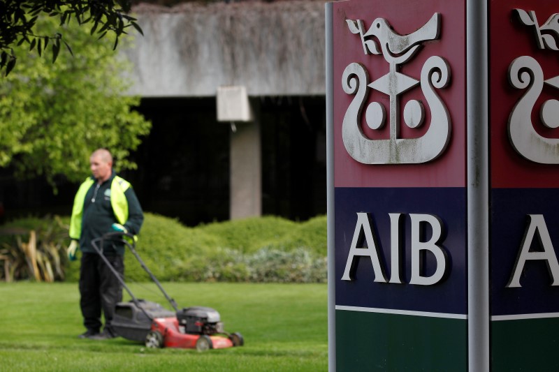 © Reuters. A gardener mows the grass outside the headquarters of AIB on the day the bank announced it's results, in Dublin