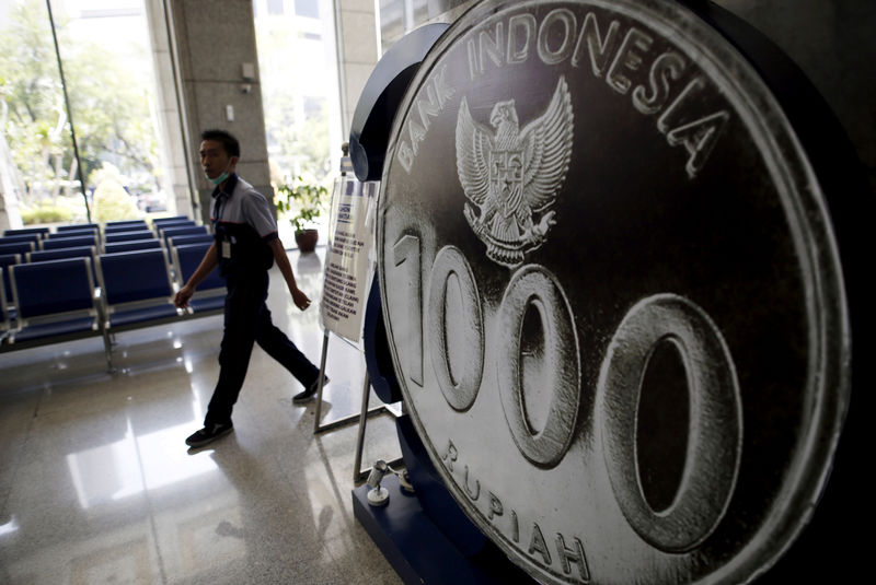 © Reuters. An employee walks past a mock one thousand rupiah coin on display at Bank Indonesia's headquarters in Jakarta, Indonesia