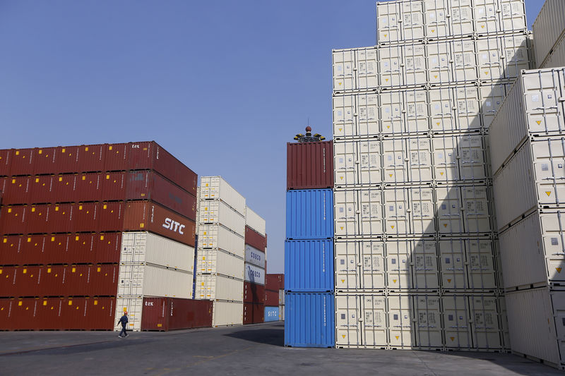 © Reuters. A man walks past container boxes at a port in Shanghai