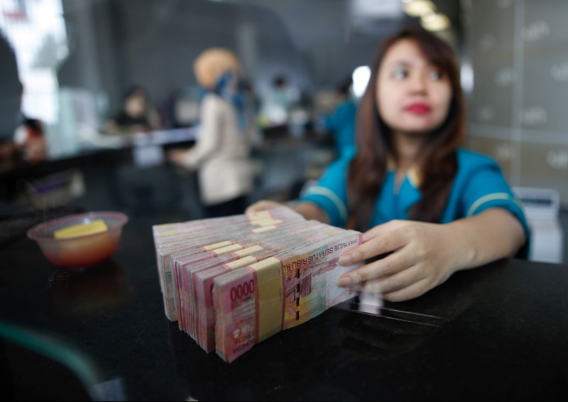 © Reuters. A teller at a money changer handles Indonesia rupiah bank notes in Jakarta, Indonesia