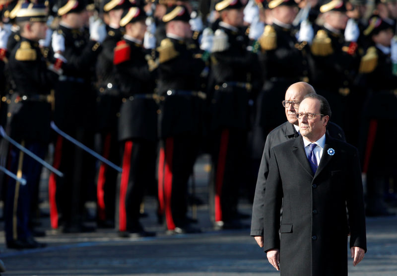 © Reuters. France's President Francois Hollande and Defence Minister Jean-Yves Le Drian review troops as they attend a commemoration ceremony for Armistice day in Paris