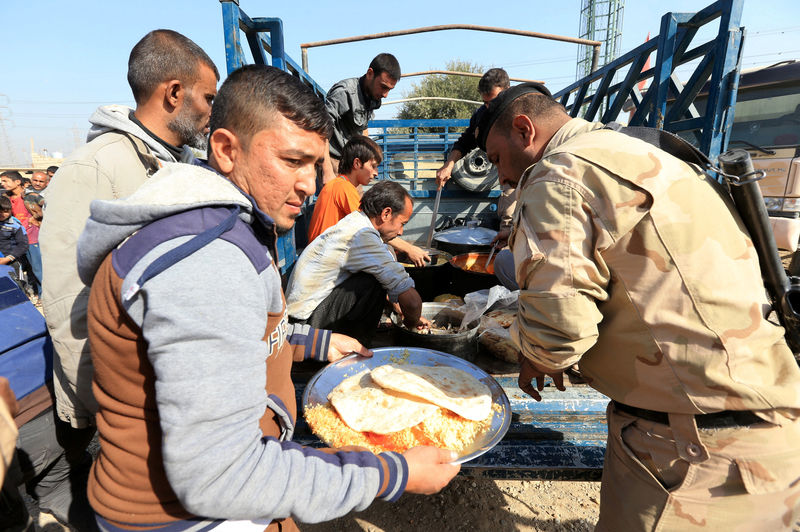 © Reuters. Displaced Iraqis receive food at Shahrezad village east of Mosul