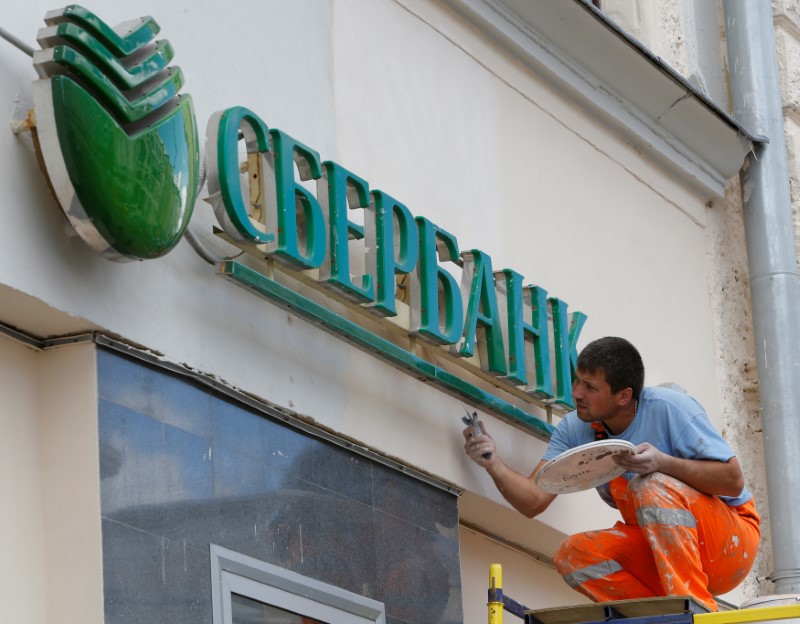 © Reuters. Worker paints facade of branch of Sberbank in Moscow