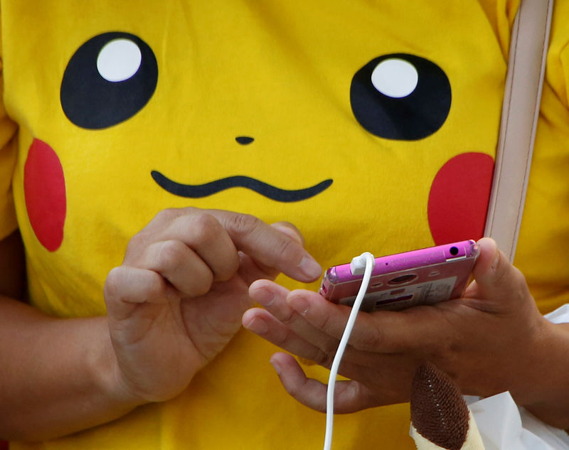 © Reuters. A woman uses a mobile phone prior to a parade where Pokemon's character Pikachu attends, in Yokoham