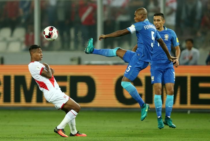 © Reuters. El jugador de la selección brasileña Fernandinho (número 5) y el peruano Andy Polo disputan el balón en el partido que ambos equipos disputaron el martes en el Estadio Nacional de Lima, Perú