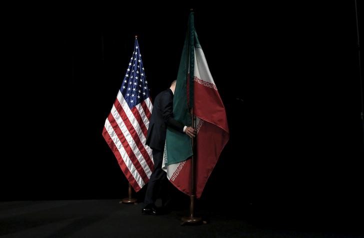 © Reuters. A staff member removes the Iranian flag from the stage after a group picture with foreign ministers and representatives during the Iran nuclear talks at the Vienna International Center in Vienna