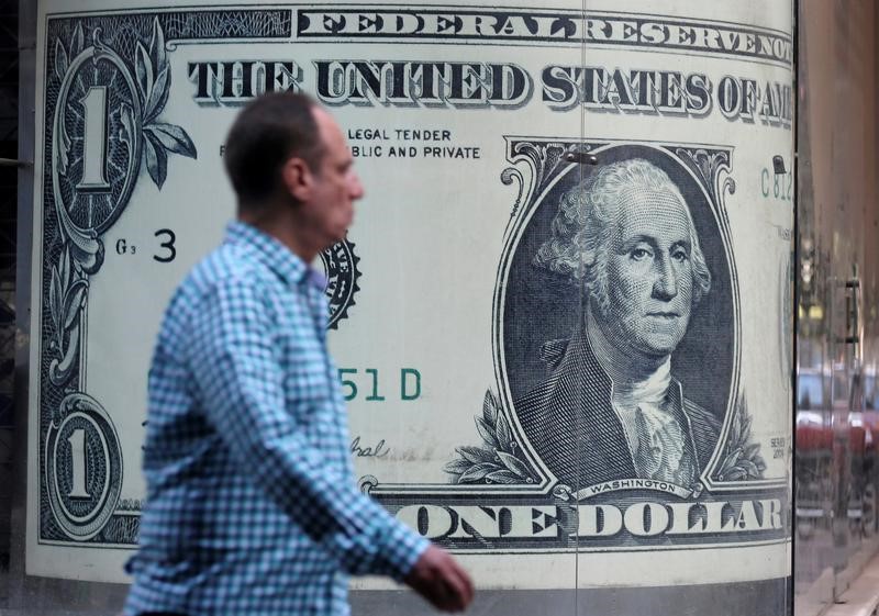 © Reuters. A man walks past a currency exchange bureau advertisement showing an image of the U.S. dollar in Cairo