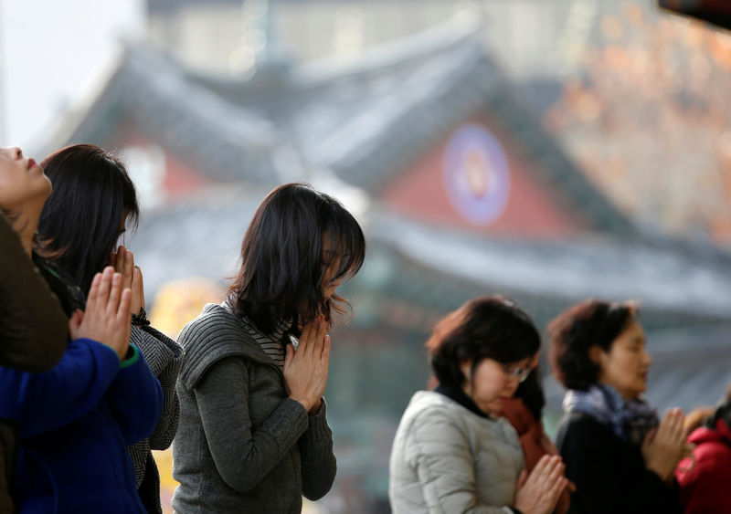 © Reuters. Women pray at a Buddhist service wishing for the success of prayers' children in the college entrance examinations at a Buddhist temple one day before the test in Seoul