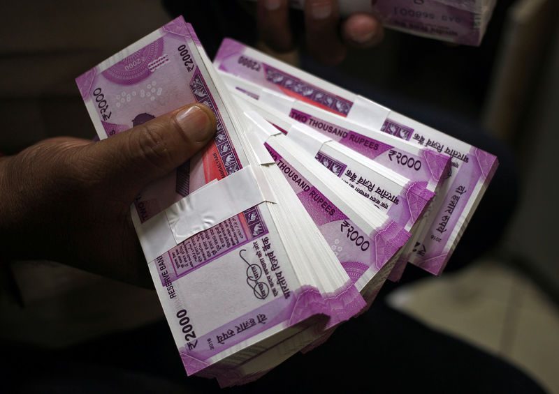 © Reuters. A cashier displays the new 2000 Indian rupee banknotes inside a bank in Jammu