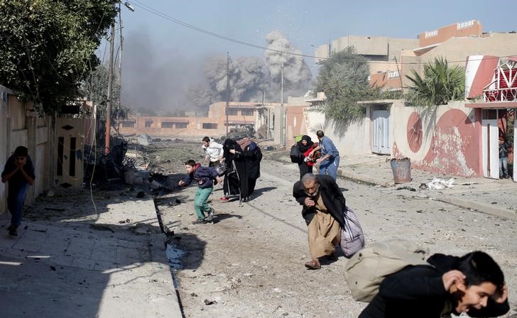 © Reuters. Pessoas correm após ataque aéreo atingir posições do Estado Islâmico em bairro de Mosul