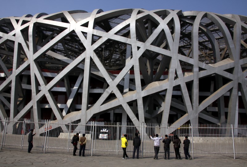 © Reuters. Chinese tourists look through a security fence at the National Stadium, which was the venue for the opening and closing ceremonies of the 2008 Olympic Games in Beijing