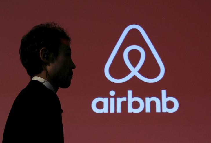 © Reuters. Homem passa em frente a logo do Airbnb em coletiva de imprensa em Tóquio, no Japão