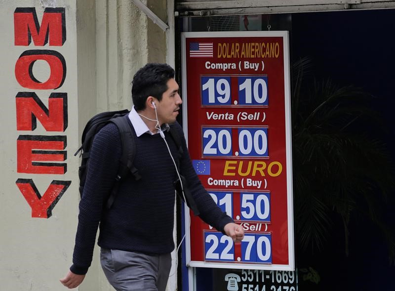 © Reuters. A man walks past a board displaying the exchange rates of Mexican peso against the U.S. dollar and the Euro at a foreign exchange house in Mexico City