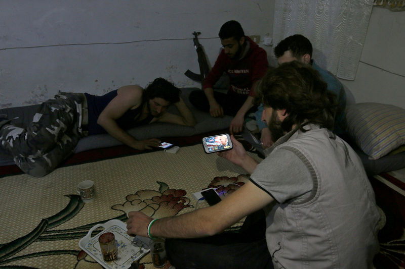 © Reuters. A Harakat Nour al-Din al-Zenki fighter watches news about Donald Trump's election as president on his smart phone in the rebel held beseiged area in Aleppo