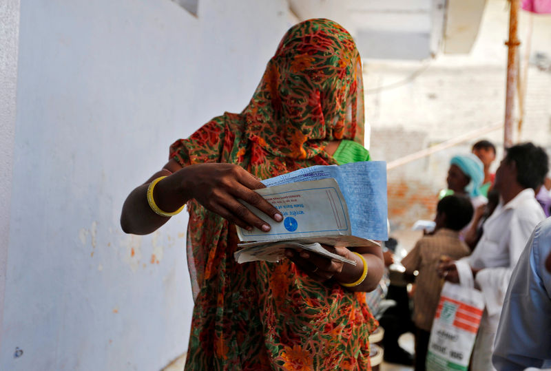 © Reuters. A woman checks her documents before depositing her old, high denomination banknotes outside a bank on the outskirts of Ahmedabad