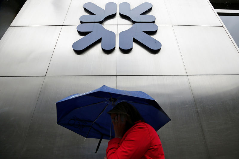 © Reuters. A woman shelters under an umbrella as she walks past a branch of RBS in the City of London