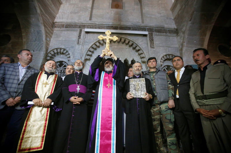 © Reuters. Iraqi Christians take part in a procession to erect a new cross over the Mar Korkeis church, after the original cross was destroyed by Islamic State militants, in the town of Bashiqa