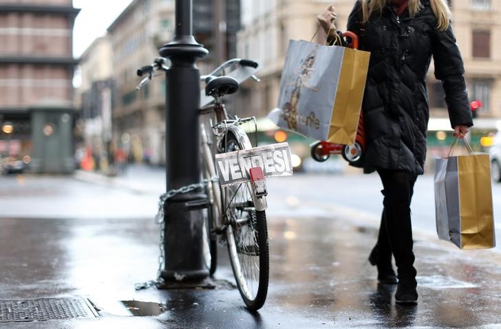 © Reuters. A woman walks past a bike with a "For sale" sign on it, in Rome