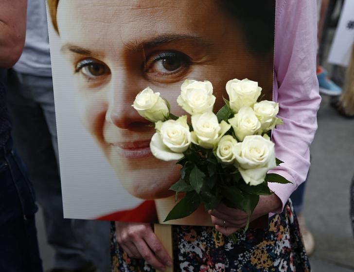 © Reuters. A woman holds a placard and white roses during a special service for murdered Labour Party MP Jo Cox, at Trafalgar Square in London