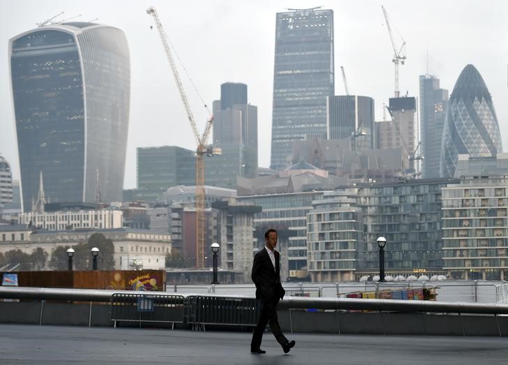 © Reuters. A man walks in front of the City of London financial district of London