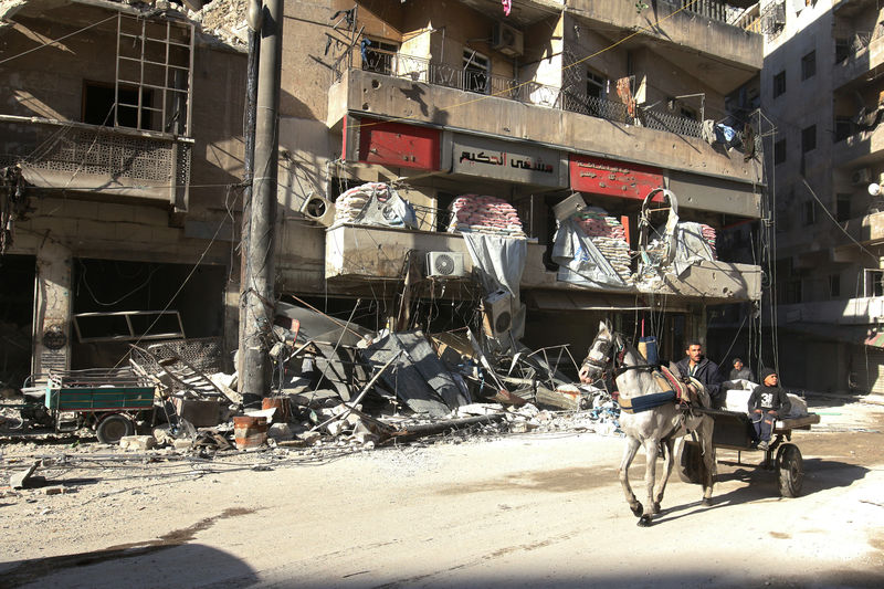 © Reuters. People ride a cart pulled by a horse near the damaged al-Hakeem hospital, in the rebel-held besieged area of Aleppo