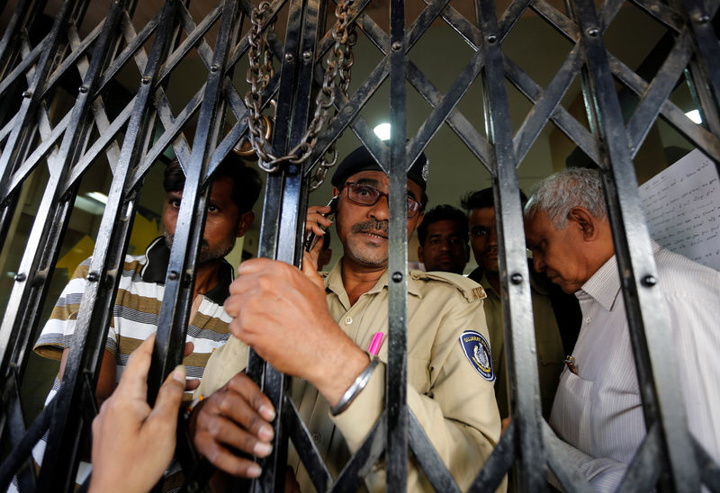 © Reuters. A policeman closes the gate from inside as people try to enter a bank in Ahmedabad