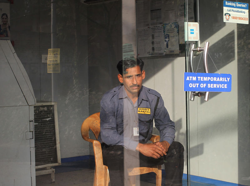© Reuters. A security guard sits inside an ATM counter which has a notice is displayed outside in Jammu