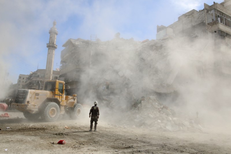 © Reuters. A Civil Defence member stands as a front loader removes debris after an air strike Sunday in the rebel-held besieged al-Qaterji neighbourhood of Aleppo