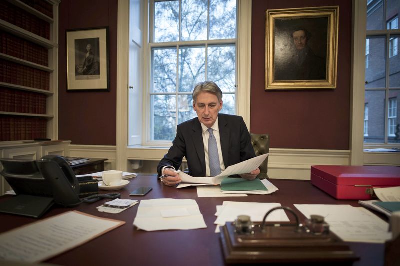© Reuters. Britain's Chancellor of the Exchequer Philip Hammond reads through his Autumn Statement as he poses for a photograph in his office in 11 Downing Street, London