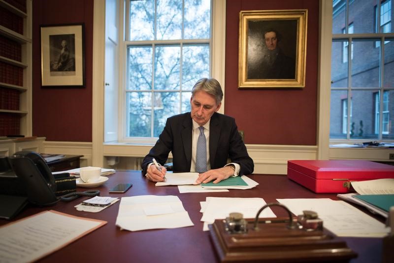 © Reuters. Britain's Chancellor of the Exchequer Philip Hammond reads through his Autumn Statement as he poses for a photograph in his office in 11 Downing Street, London