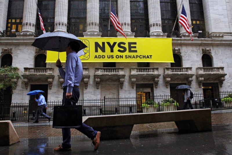 © Reuters. Morning commuters pass by the New York Stock Exchange on a rainy morning in New York City