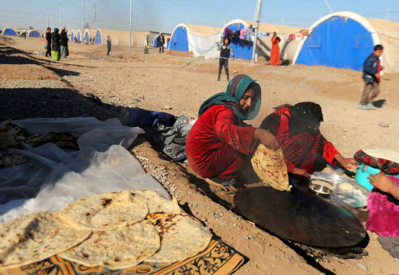 © Reuters. Displaced Iraqis, who fled the Islamic State stronghold of Mosul, bake bread outside their tent at Khazer camp