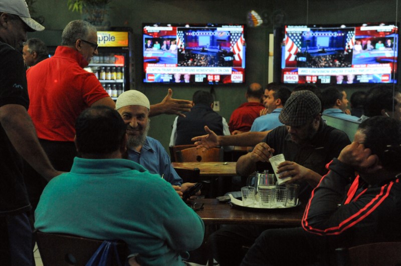 © Reuters. Men great each other before the start of the U.S. presidential debate at a restaurant in the Queens borough of New York City