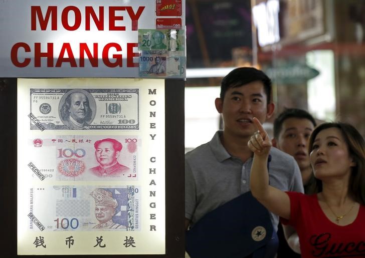 © Reuters. People look at the exchange rate at a Moneychanger displaying posters of U.S. dollars, Chinese Yuan and Malaysia Ringgit in Singapore