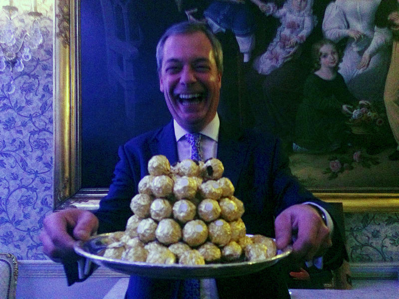© Reuters. Nigel Farage, the interim leader of the United Kingdom Independence Party (UKIP) holds a platter of Ferrero Rocher chocolates during a party in London