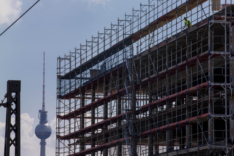 © Reuters. A worker is seen behind scaffoldings at a construction site near the Fernsehturm TV tower in Berlin