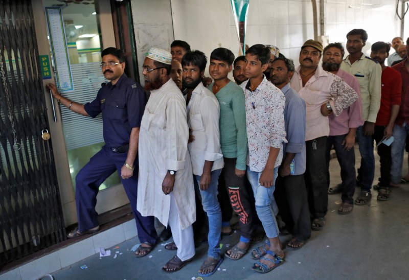 © Reuters. People queue as they wait for their turn to exchange or deposit their old high denomination banknotes outside a bank in Mumbai