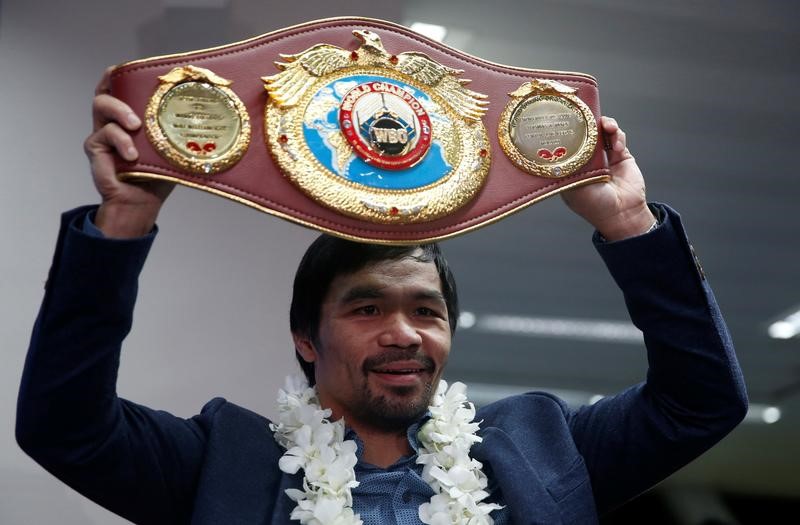 © Reuters. Filipino boxer and Senator Manny Pacquiao raises his boxing winning belt during a news conference upon arrival, after winning WBO welterweight bout with Jessie Vargas, at Ninoy Aquino International airport in Paranaque, Metro Manila