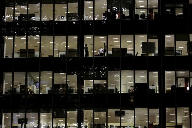 © Reuters. Workers are seen in office windows in the financial district of Canary Wharf in London