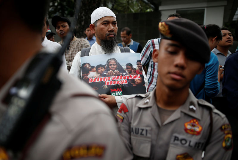 © Reuters. A protester stands behind police during a demonstration against what organisers say is the crackdown on ethnic Rohingya Muslims in Myanmar, outside the Myanmar embassy in Jakarta, Indonesia