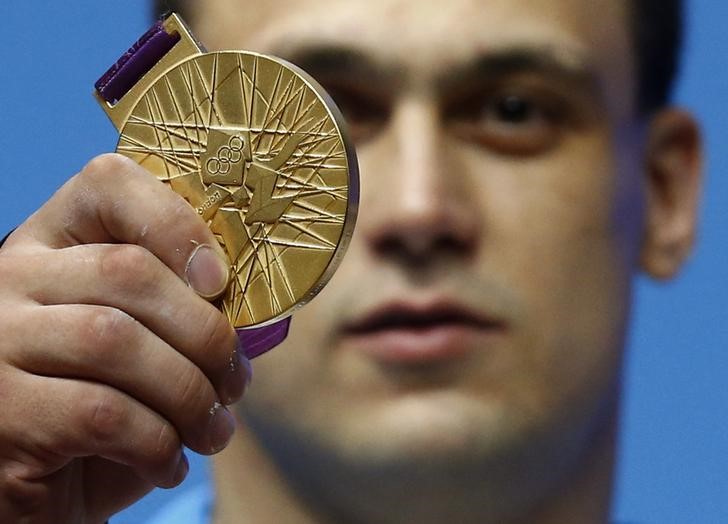 © Reuters. Kazakhstan's Ilya Ilyin poses with his gold medal of the men's 94Kg weightlifting competition at the ExCel venue at the London 2012 Olympic Games