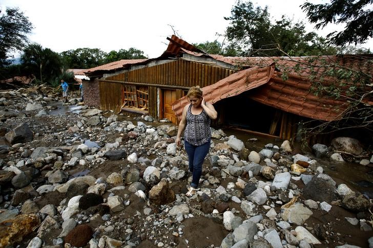 © Reuters. Mulher caminha diante de casas após passagem do furacão Otto em Guayabo de Bagaces