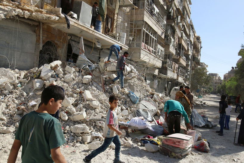© Reuters. People remove belongings from a damaged site after an air strike Sunday in the rebel-held besieged al-Qaterji neighbourhood of Aleppo